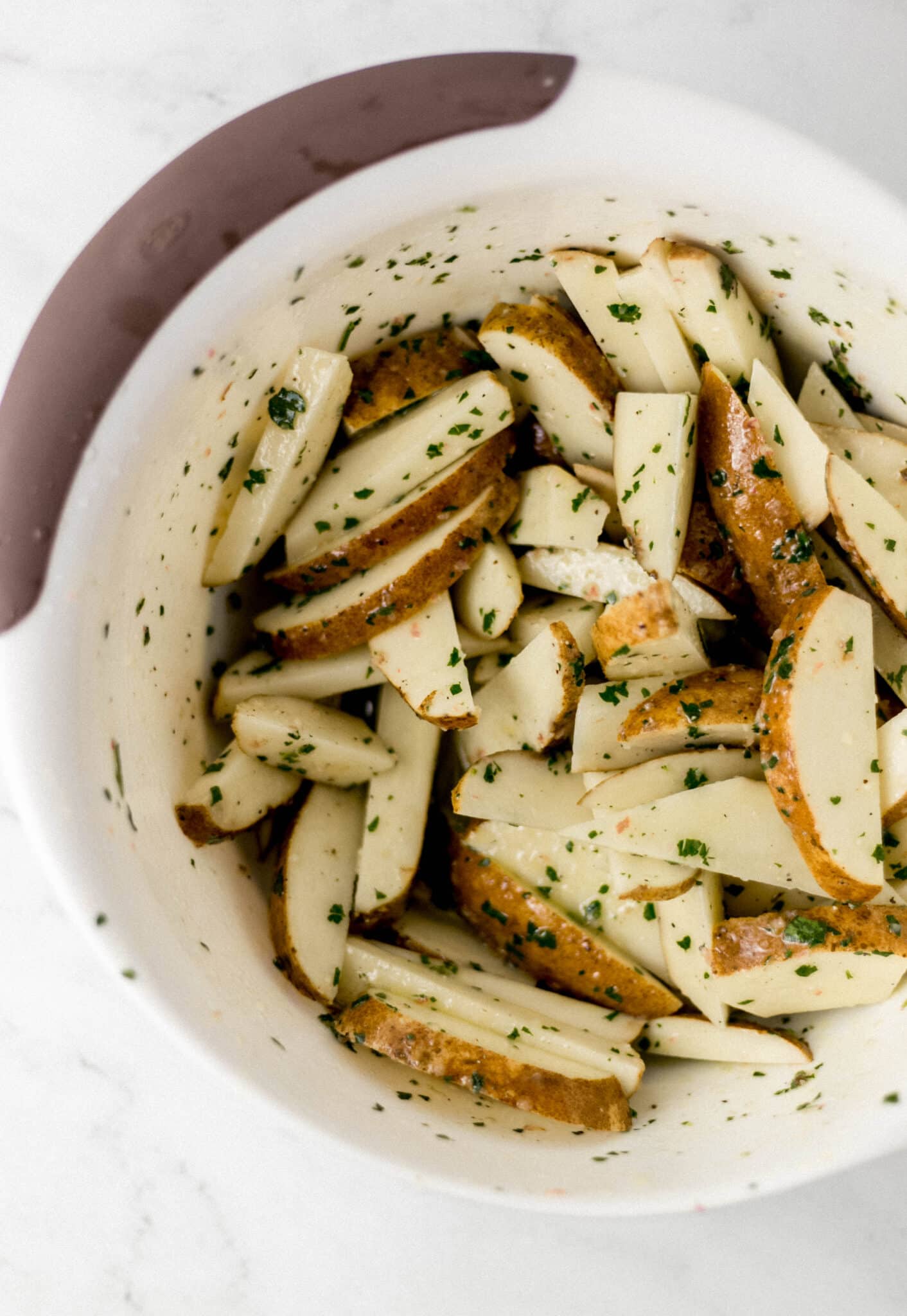 potatoes combined with sauce ingredients in large white bowl