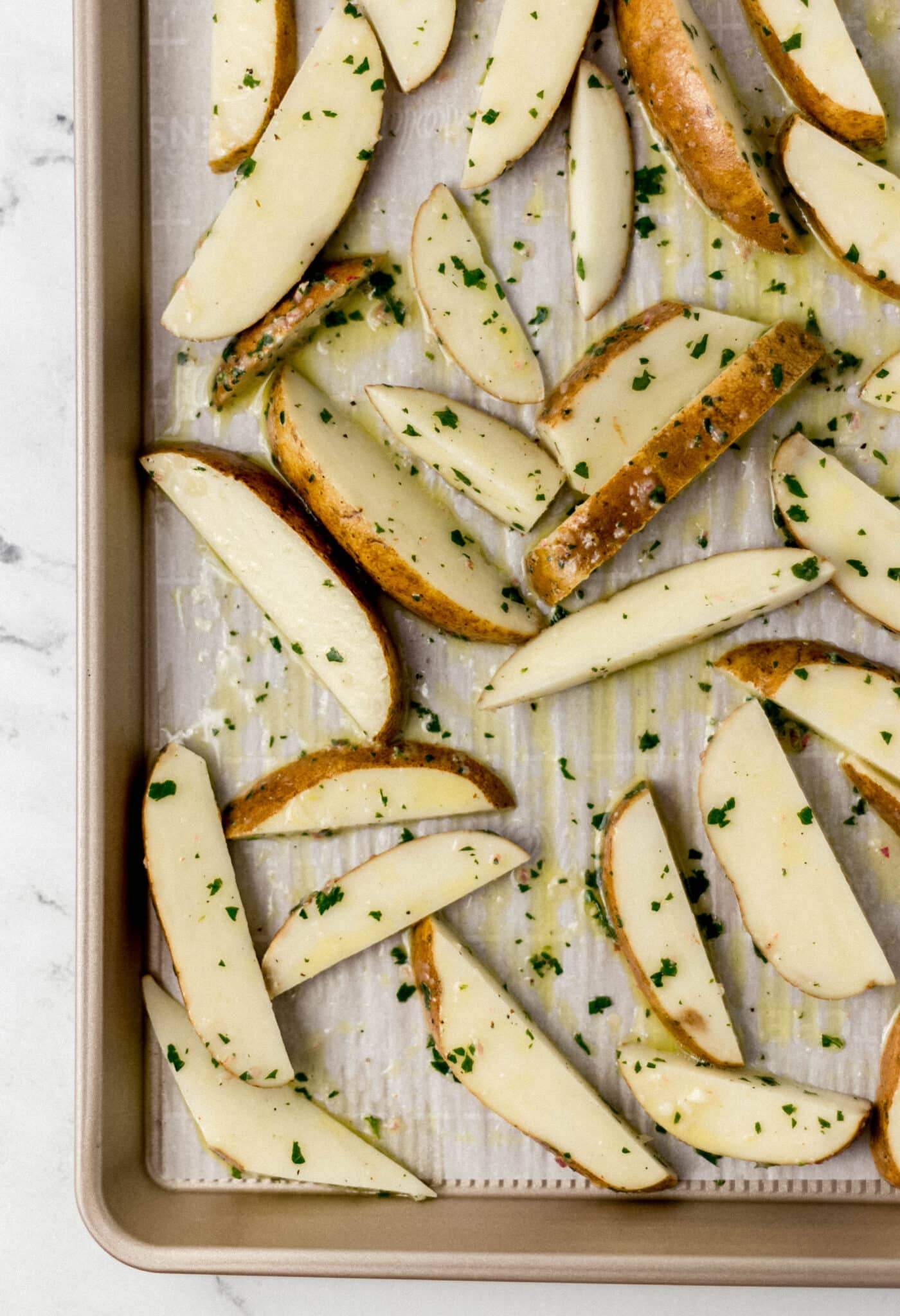 unbaked potatoes on parchment lined baking sheet