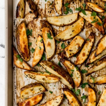 overhead view finished Greek potatoes on parchment lined baking sheet