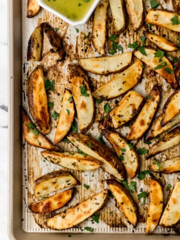 overhead view finished Greek potatoes on parchment lined baking sheet