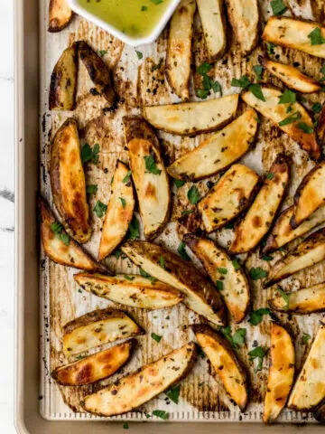overhead view finished Greek potatoes on parchment lined baking sheet