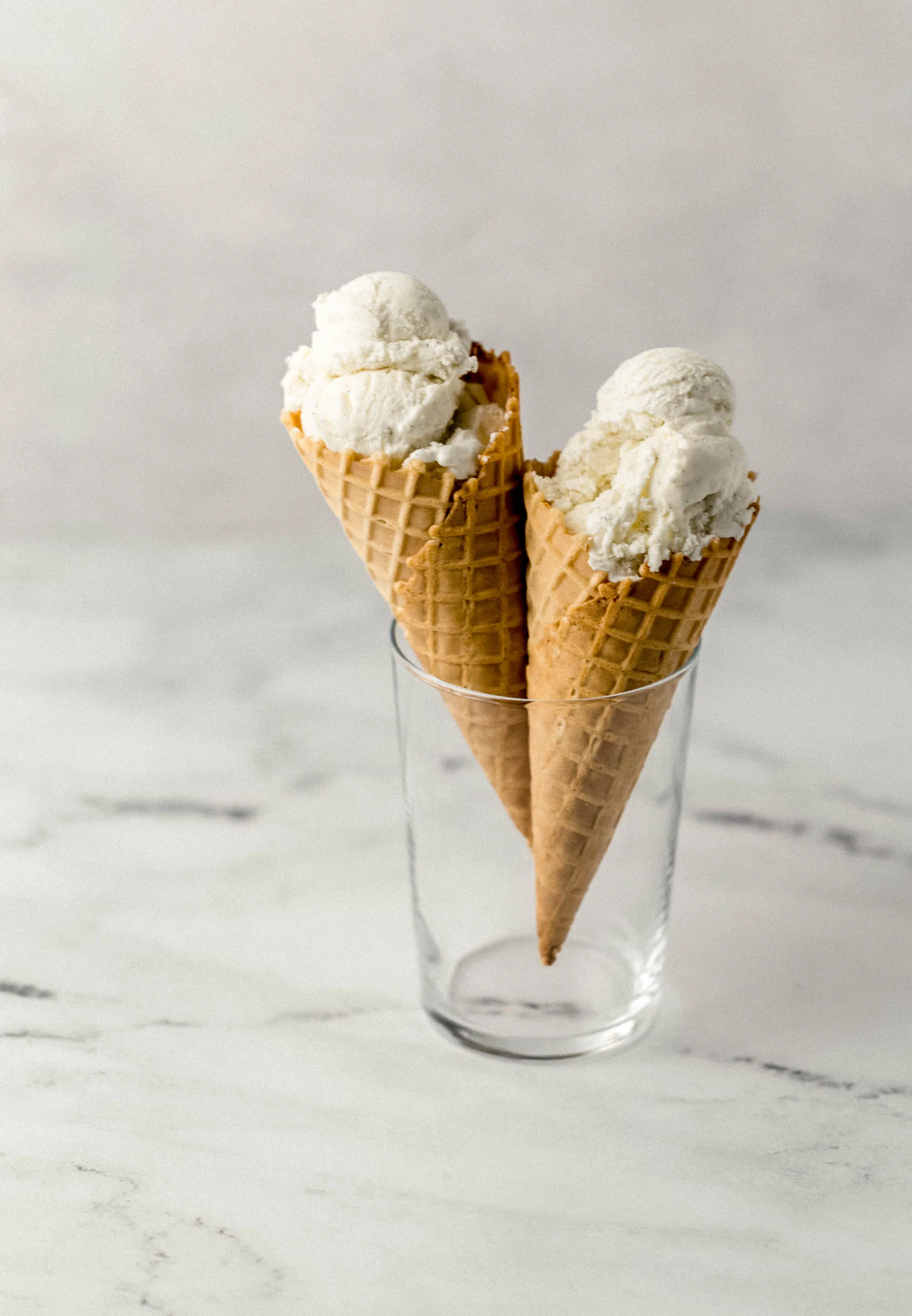 two ice cream cones in a glass on marble surface