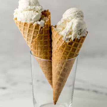 two ice cream cones with vanilla ice cream scoops in a glass