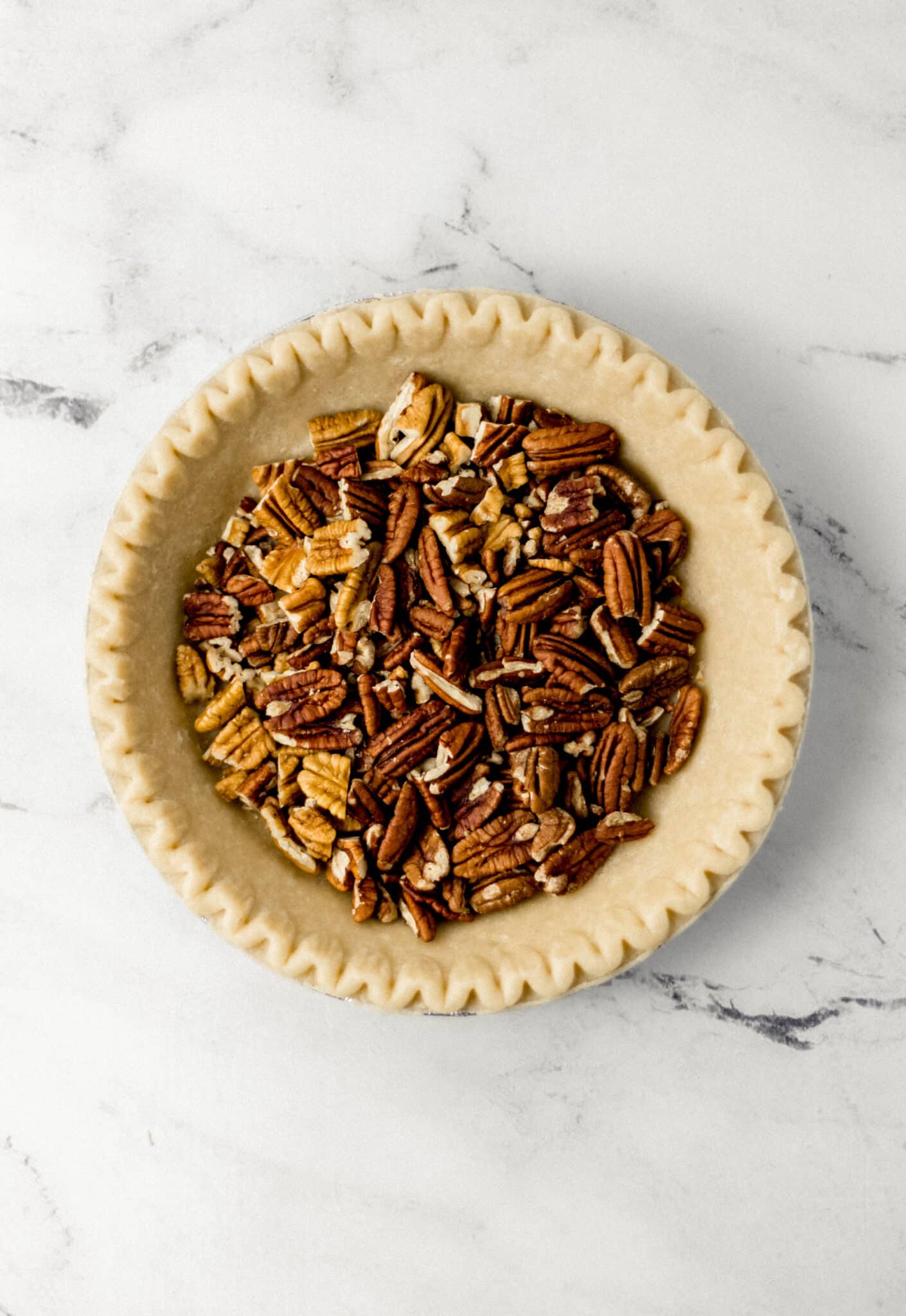 pecans added to unbaked pie crust in pan