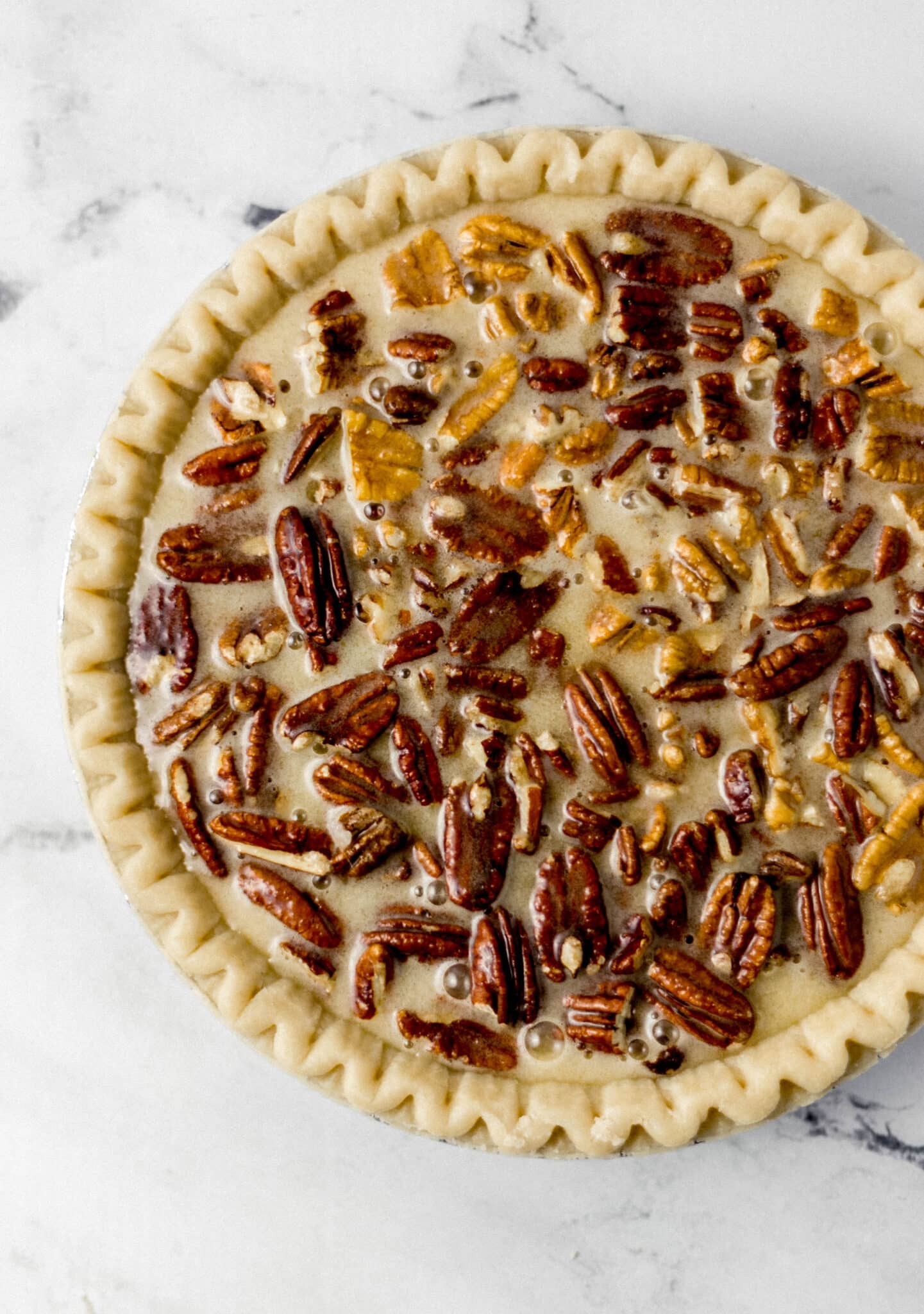 filling poured into pie crust with pecans