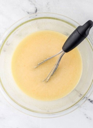 Overhead view of pie mixture in glass mixing bowl with whisk.