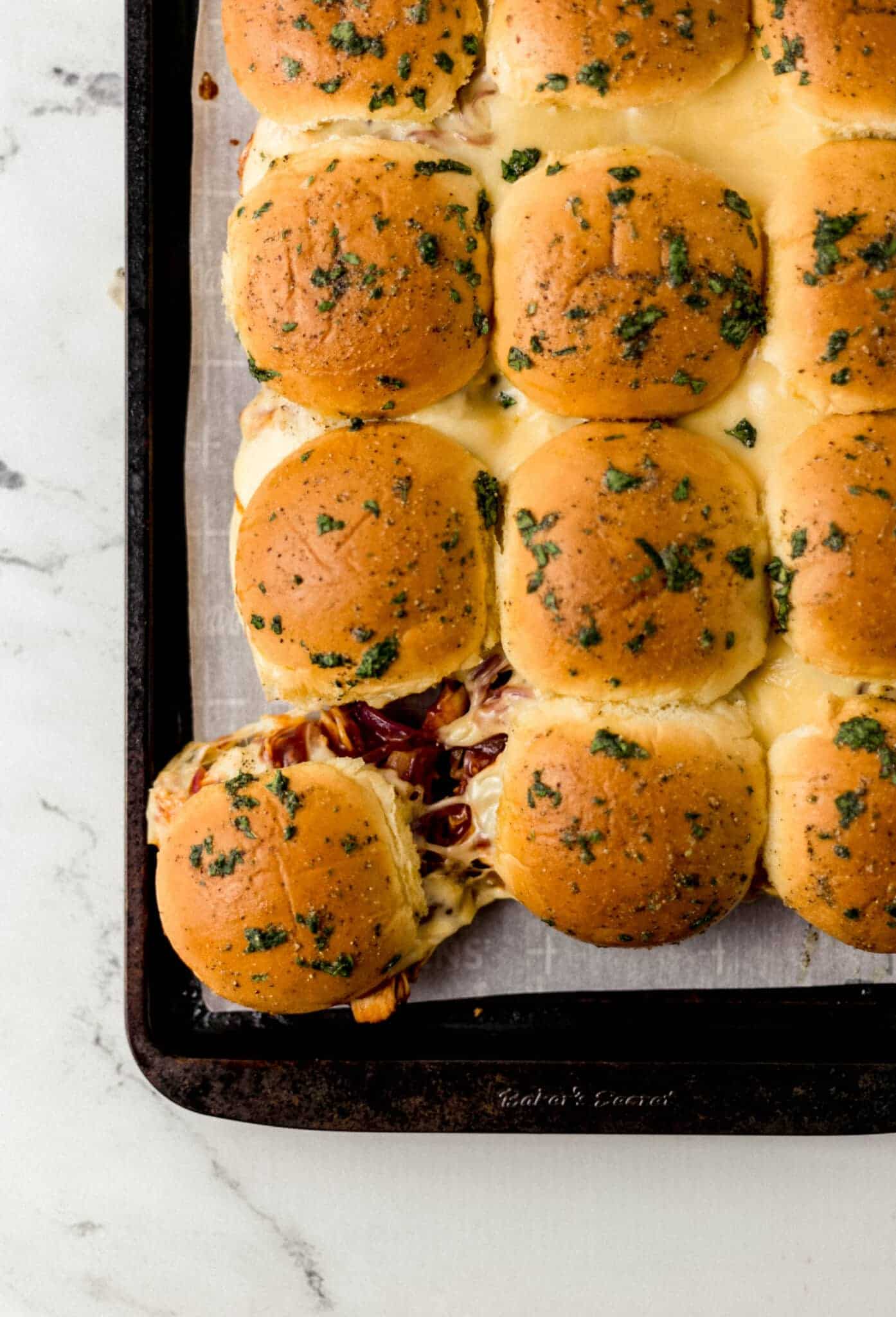 overhead view of finished bbq chicken sliders on parchment lined sheet pan 