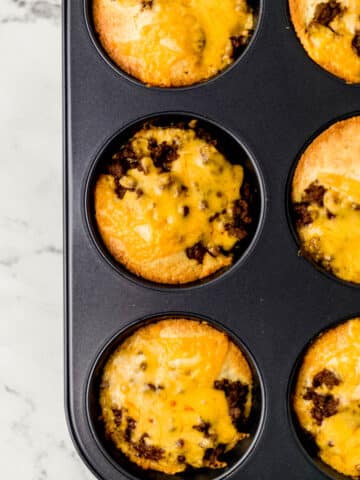 overhead view of barbecue cornbread muffins in muffin pan topped with melted cheese