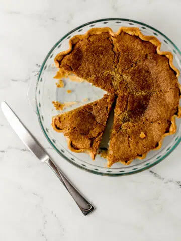 overhead view of finished sugar pie with pieces cut out of it beside a knife