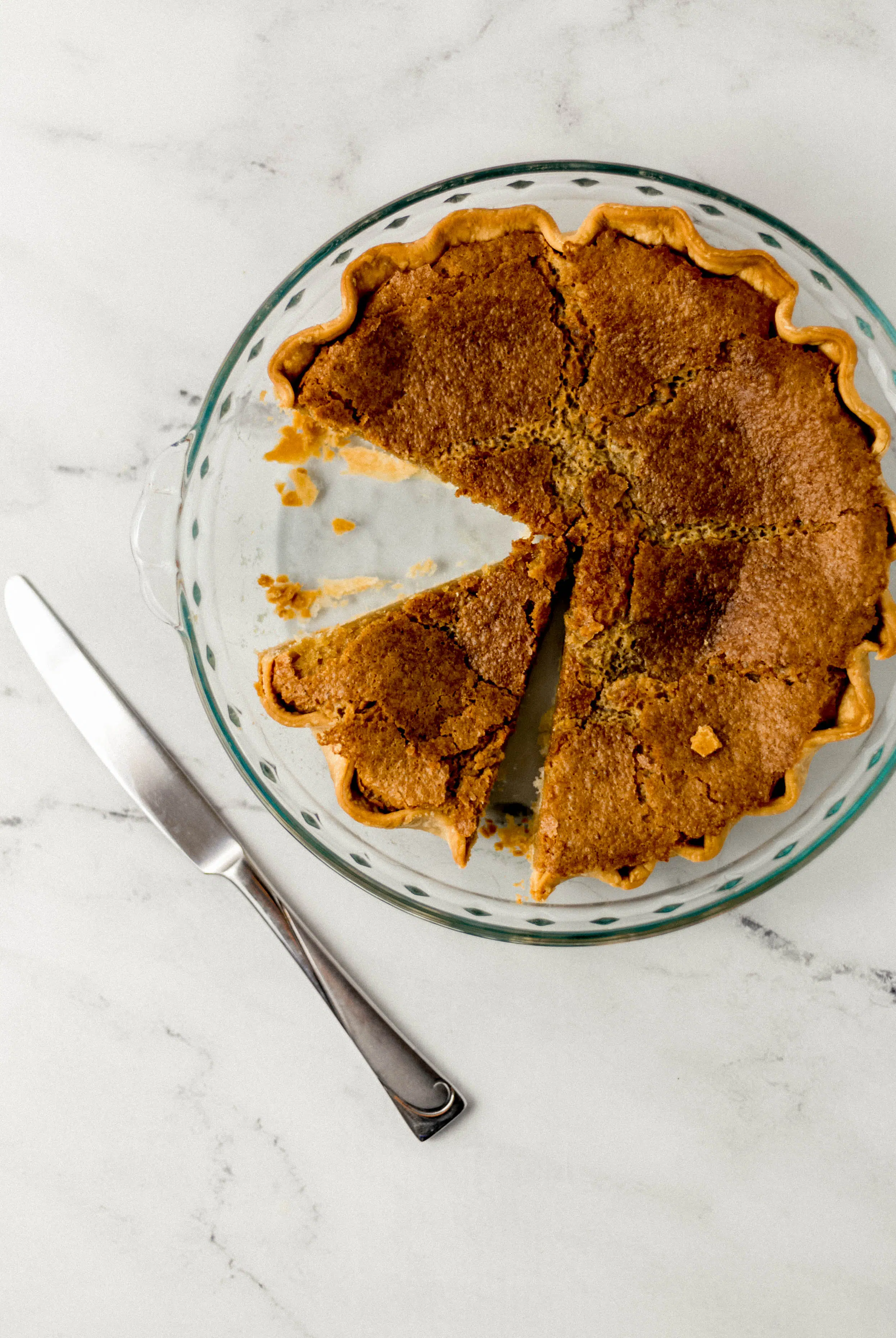 finished pie with pieces cut out of it beside a knife 