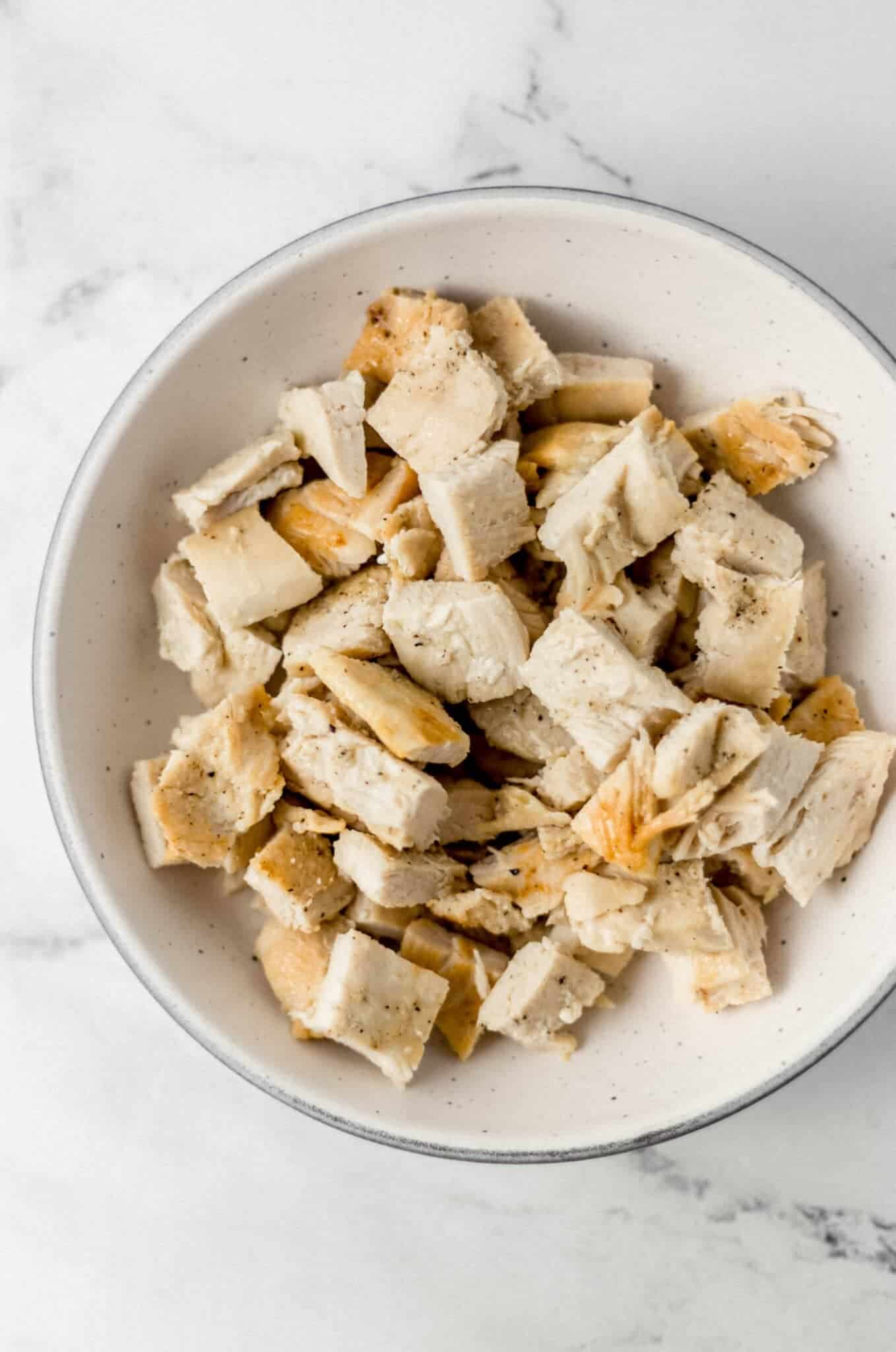 cooked chicken that is cut up in a white bowl 