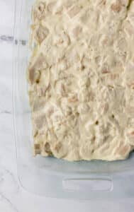 Sauce covered chicken added to a glass rectangle baking dish.