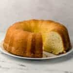 side view of pound cake with slices cut out of it on white plate