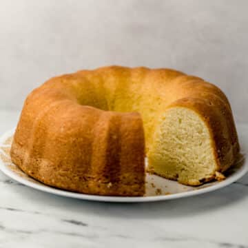 side view of pound cake with slices cut out of it on white plate
