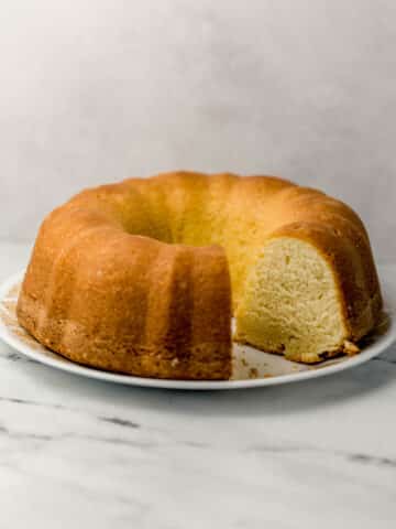 side view of pound cake with slices cut out of it on white plate