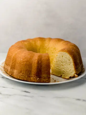side view of pound cake with slices cut out of it on white plate