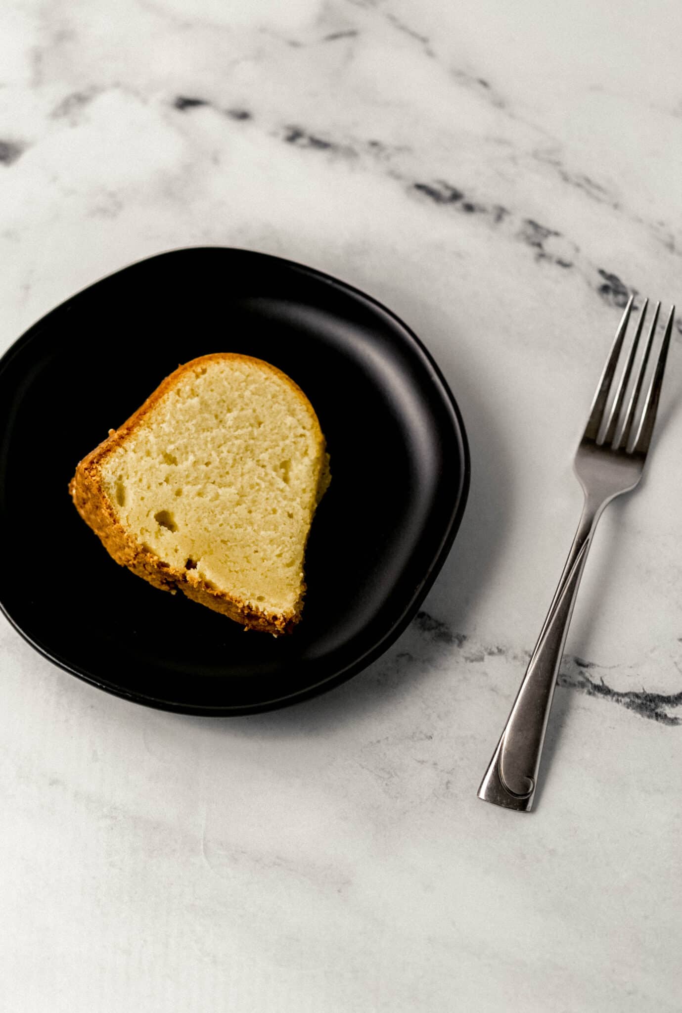 slice of cake on black plate with a fork beside it
