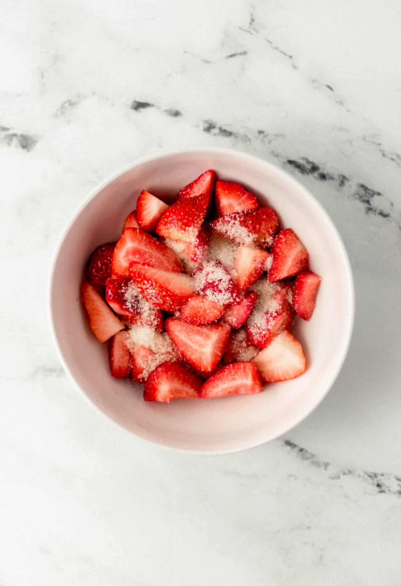 strawberries and sugar in a white bowl