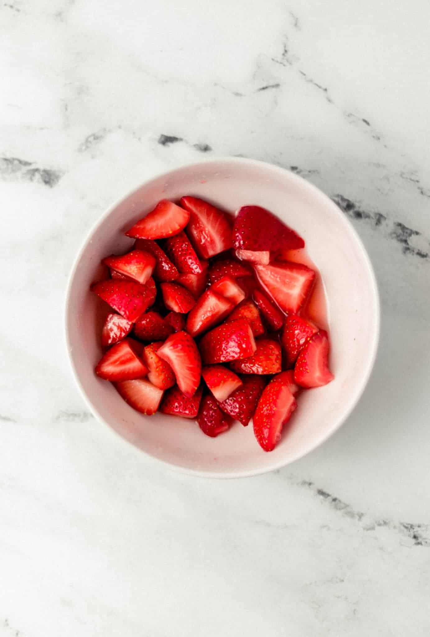 strawberries in white bowl that was combined with sugar and sat for a few minutes 