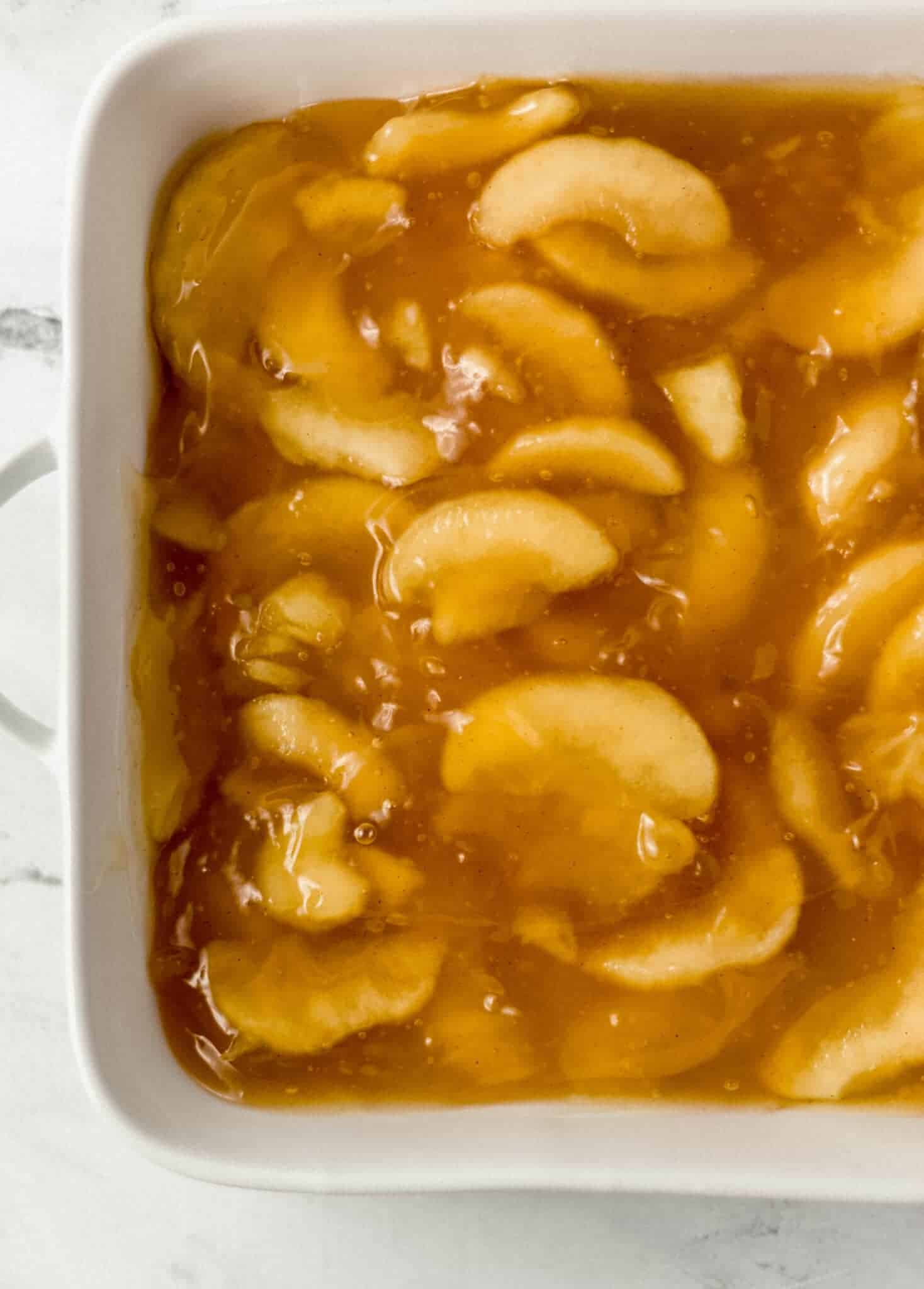 apple pie filling spread evenly on the bottom of a white baking dish