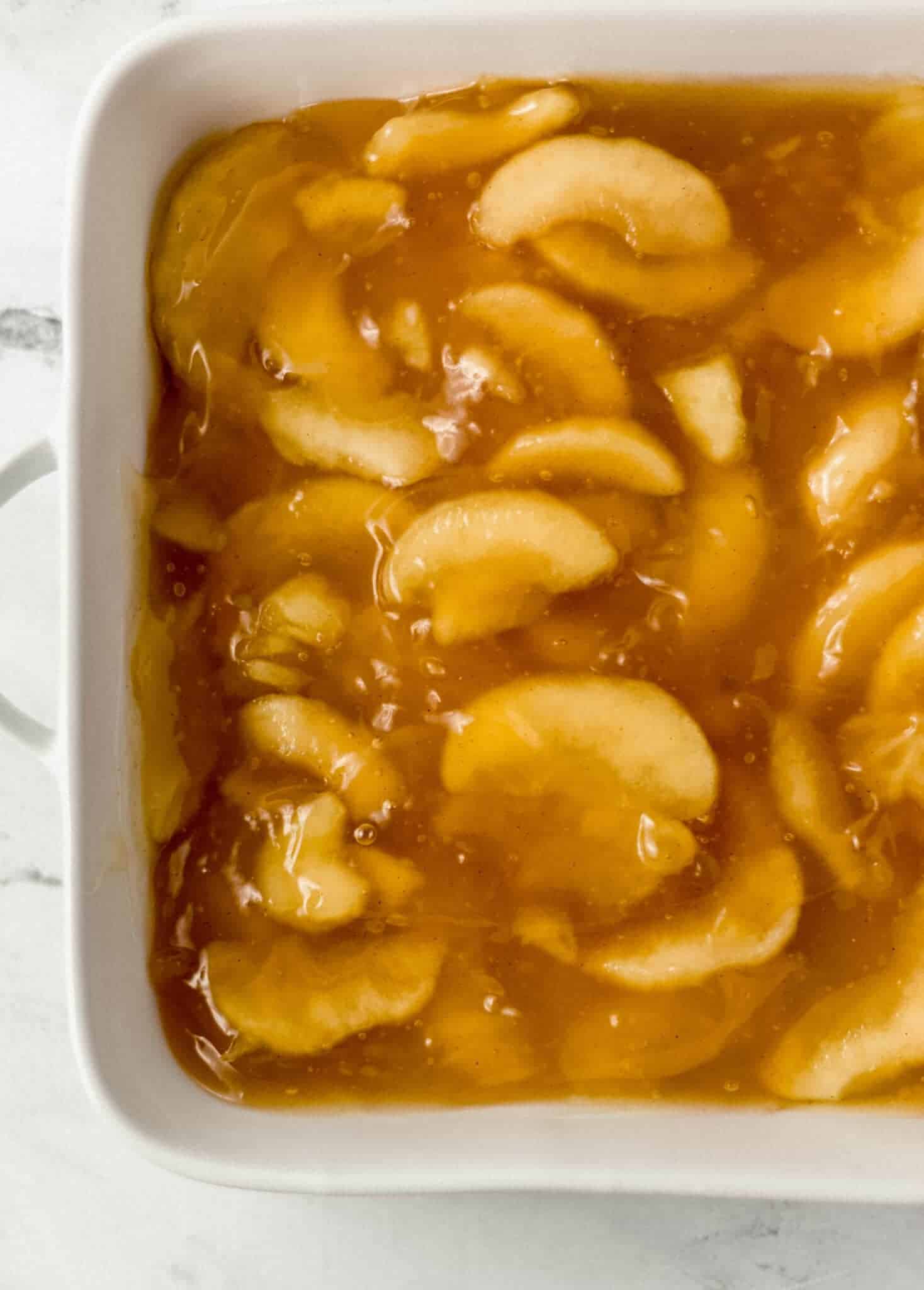 apple pie filling spread evenly on the bottom of a white baking dish 