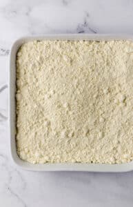 Overhead view of cake mix added to baking dish.