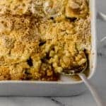 close up side view of finished apple dump bake with serving spoon in it.