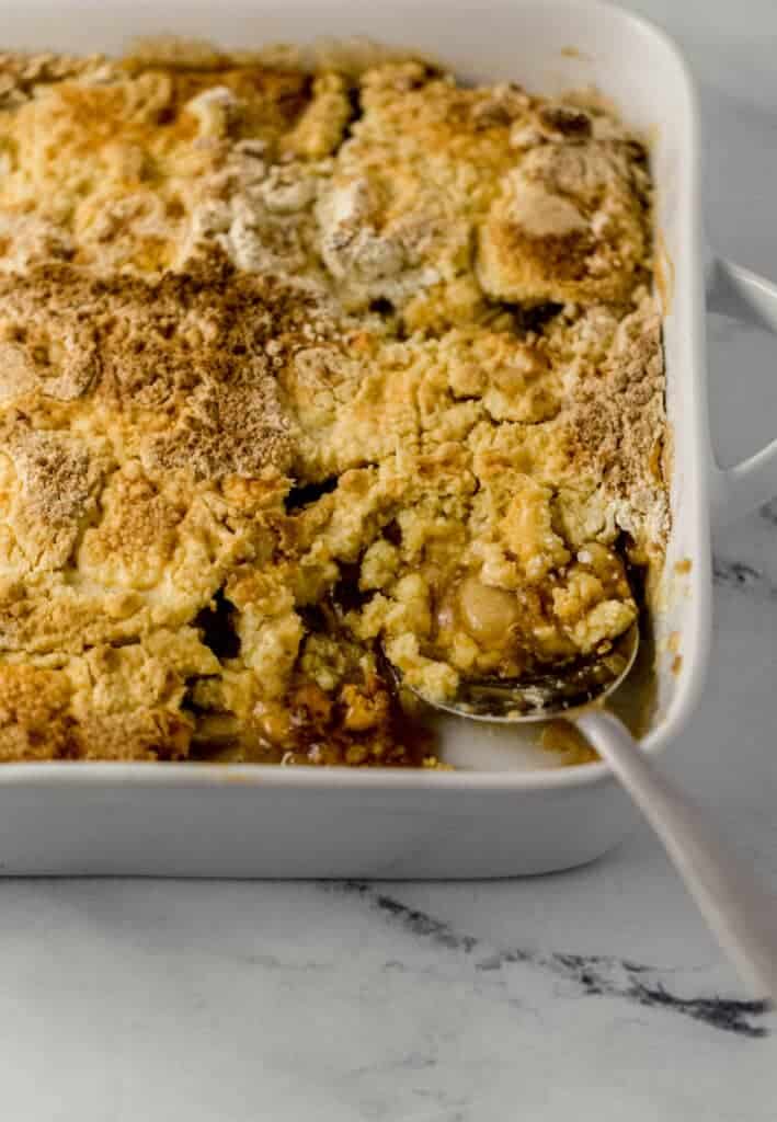 close up side view of finished apple dump bake with serving spoon in it.