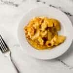 overhead view of single serving of apple dump cake on small white plate beside a fork