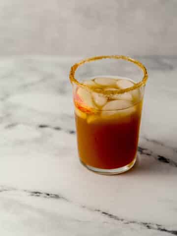 close up side view of apple ginger margarita in glass with ice