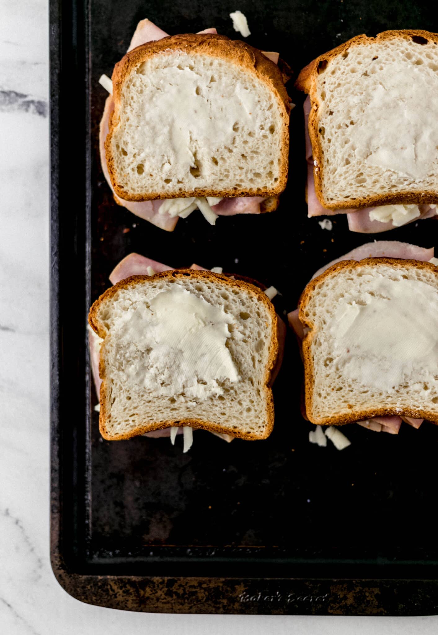 sandwiches topped with butter on baking sheet