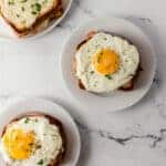 overhead view of finished croque madame sandwiches on white plates