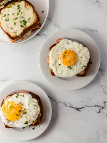 overhead view of finished croque madame sandwiches on white plates