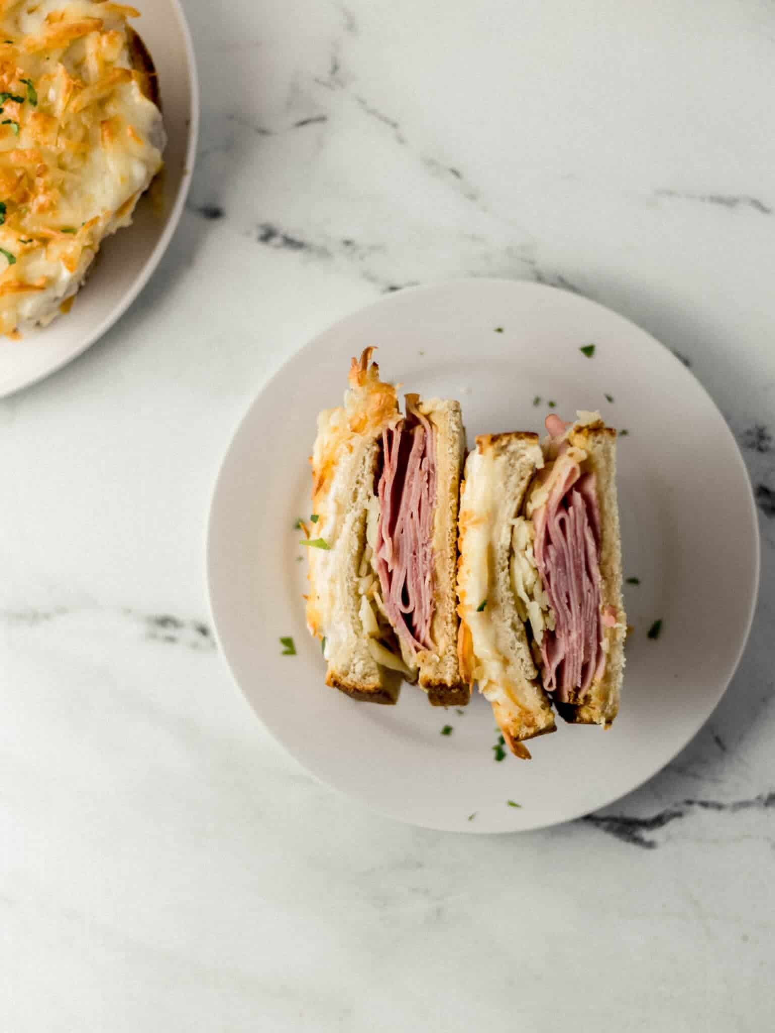 overhead view of sandwich cut in half on white plate with another in the background