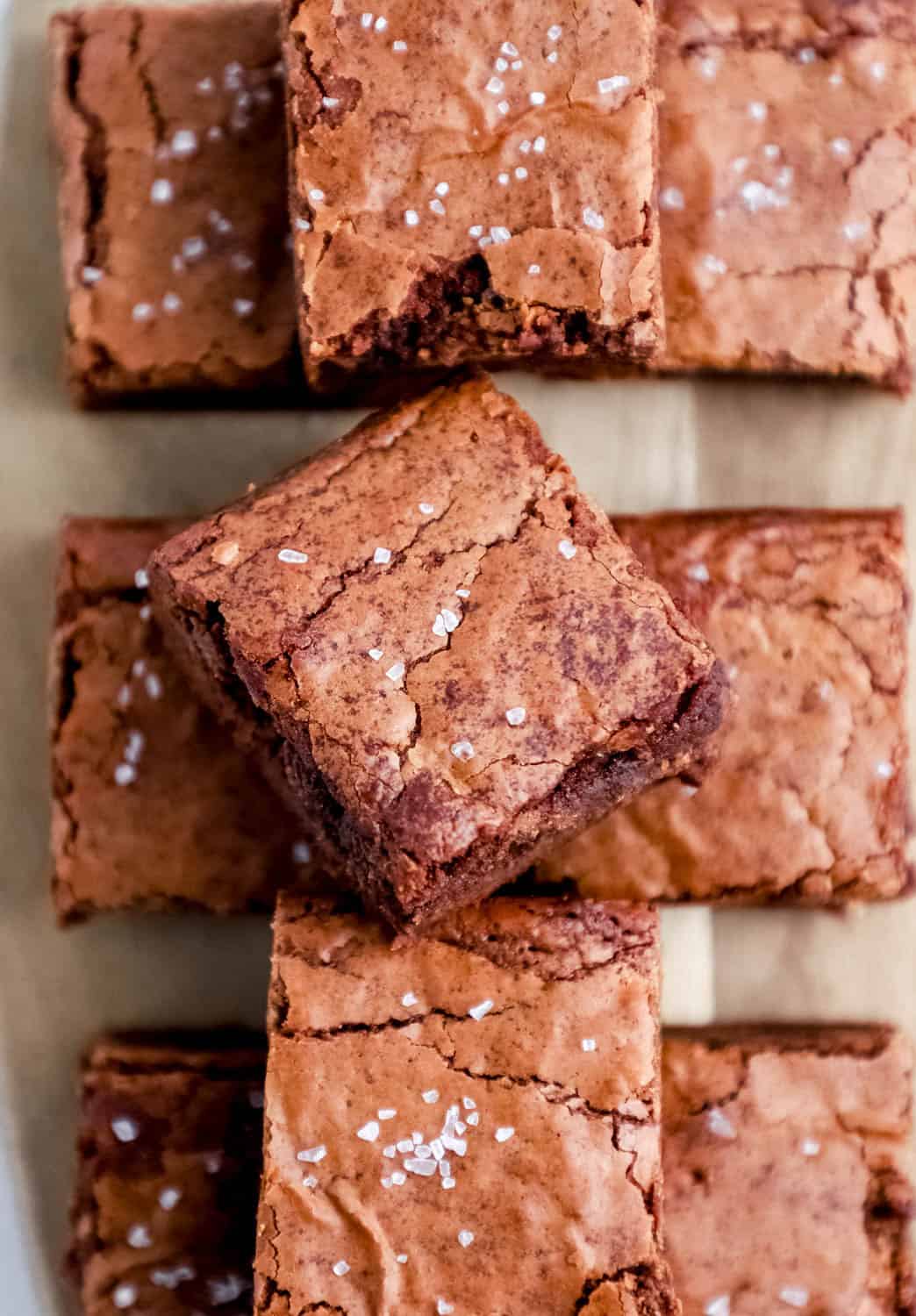 Cut brownies stacked on wooden cutting board. 