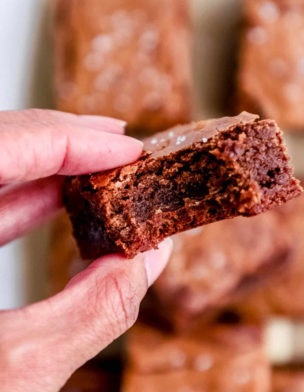 Hand holding brownie with bite in it. 