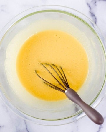 Wet ingredients combined in glass mixing bowl with whisk.