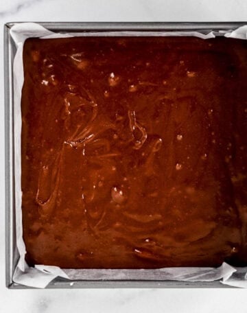 Brownie mixture added to parchment lined baking pan.