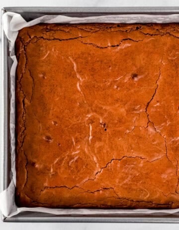 Overhead view of baked brownies in parchment lined baking pan.