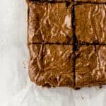 overhead view of finished fudgy brownies cut into small squares on parchment paper