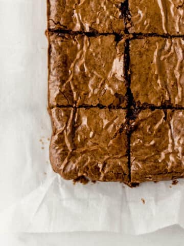 overhead view of finished fudgy brownies cut into small squares on parchment paper