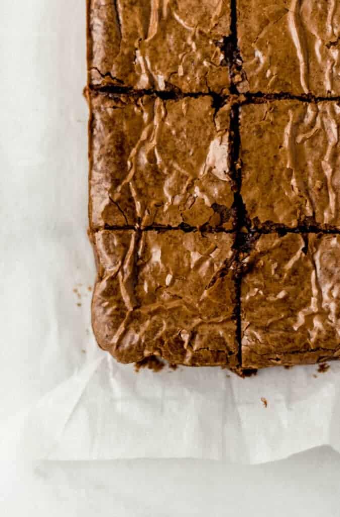 overhead view of finished fudgy brownies cut into small squares on parchment paper