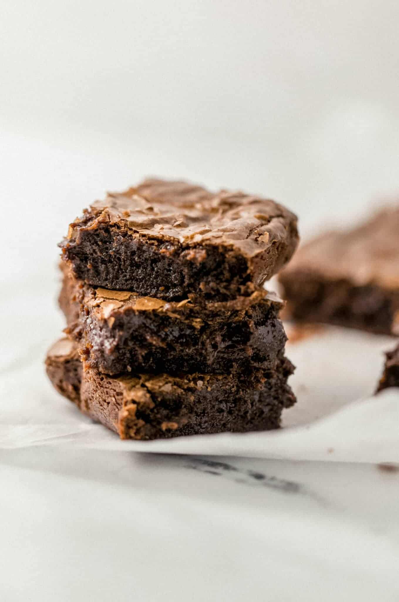 three brownies stacked on top of each other on parchment paper.