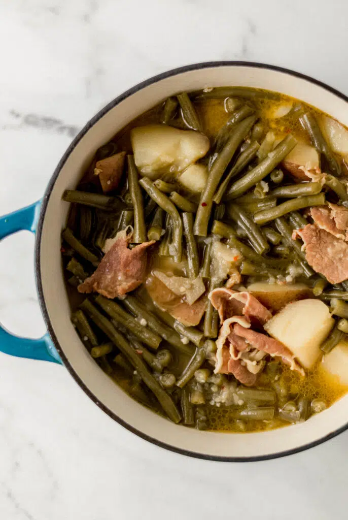 overhead view of finished ham, green beans, and potatoes in large pot