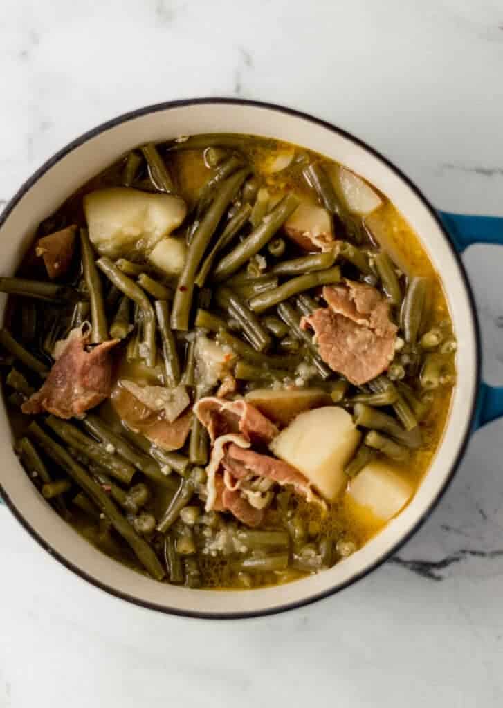 overhead view of green beans in large pot on marble surface 