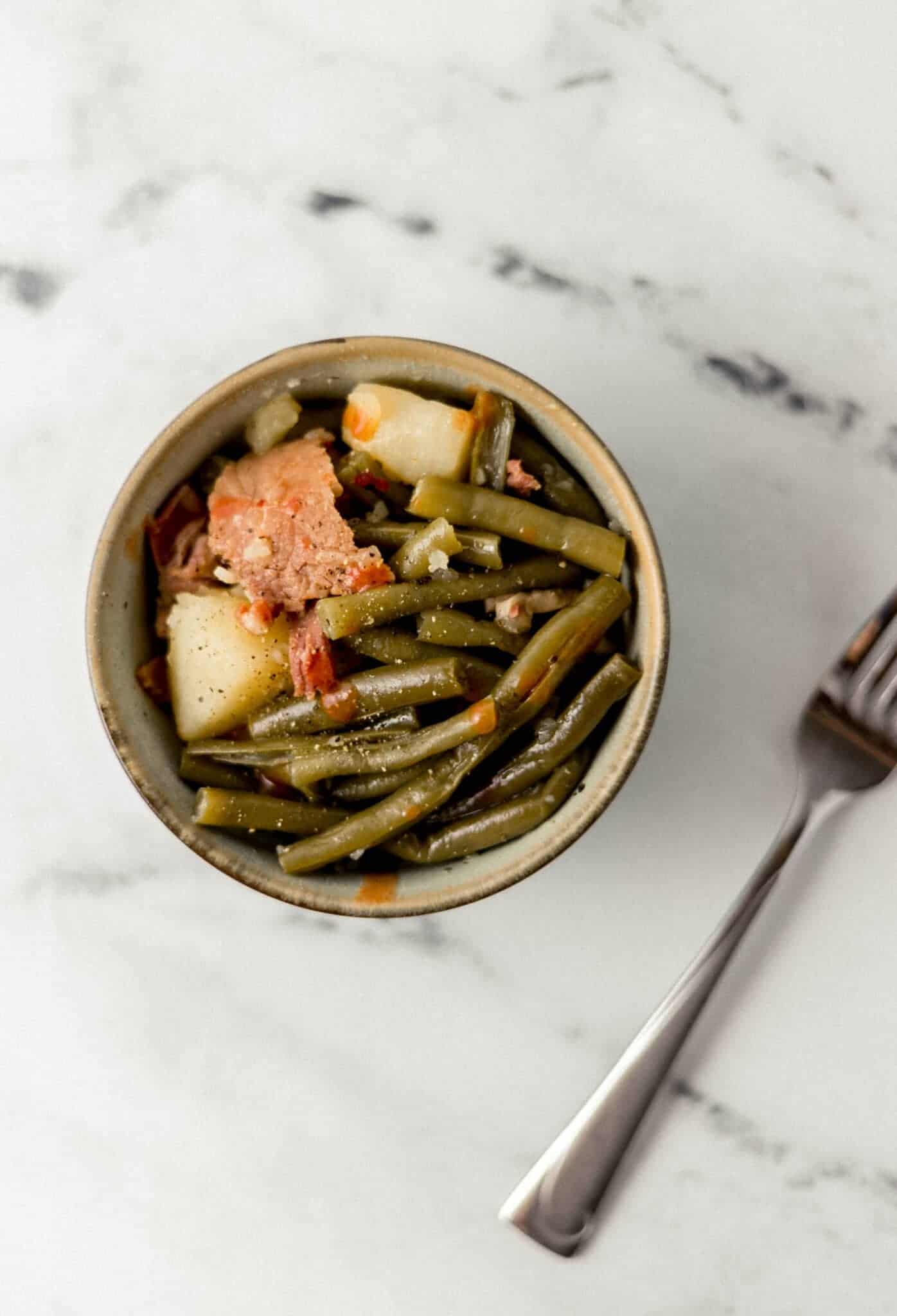 single serving of green beans in a small bowl beside a fork