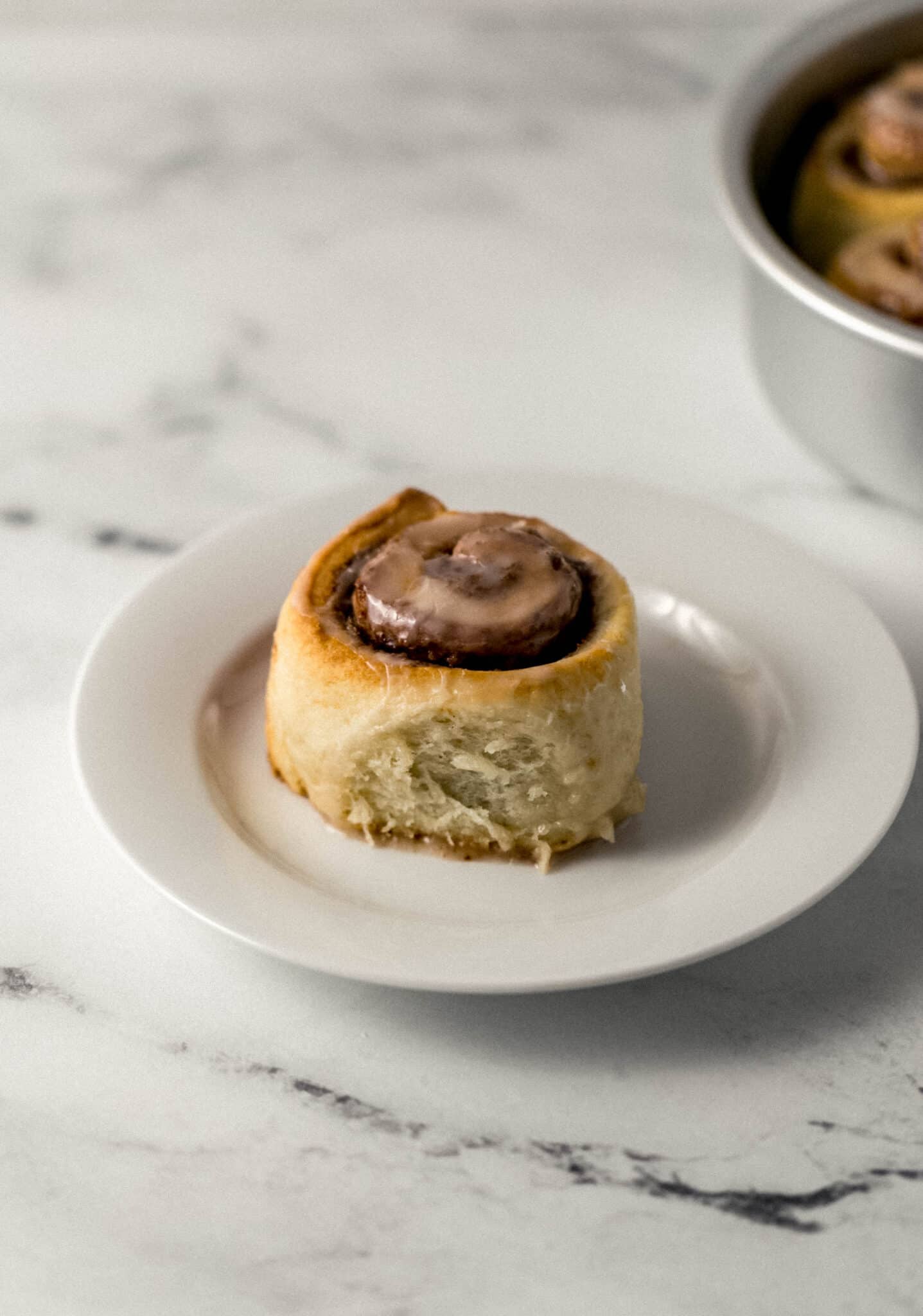 single cinnamon roll on white plate 