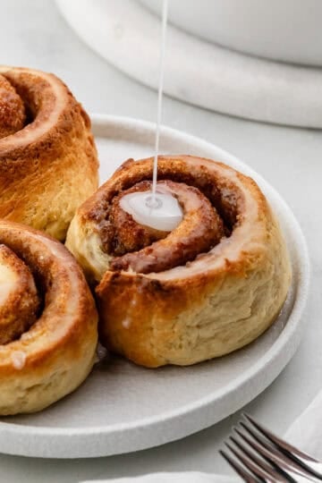 Close up view of cinnamon rolls topped with icing.