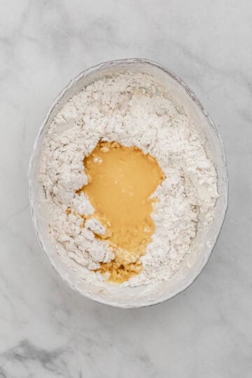 Cinnamon rolls ingredients combined in large white bowl.