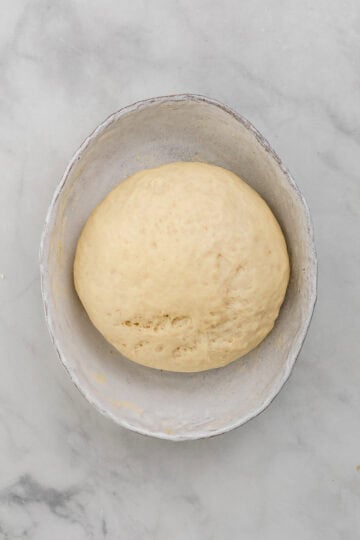 Overhead view of risen dough in large white mixing bowl.